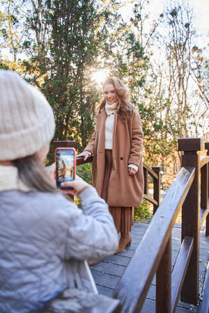 Little girl holding smartphone and shooting her mother at the park