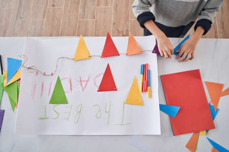 Caucasian child standing at the table and preparing holiday decor and placard for the Fathers dayの写真素材