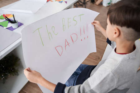 Caucasian boy holding placard with The best dad sign for the fathers dayの写真素材