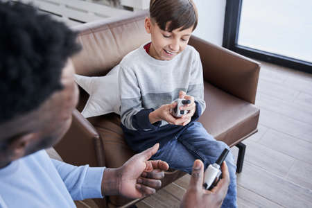 Boy examining walkie-talkie while playing with his multiracial father during the weekendの写真素材