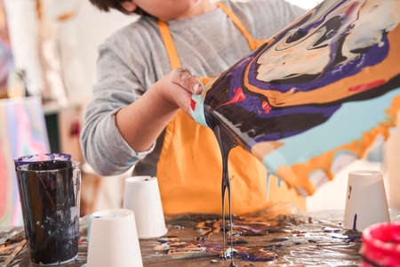 Little caucasian boy of preschool age holding canvas while drawing picture at the fluid art...