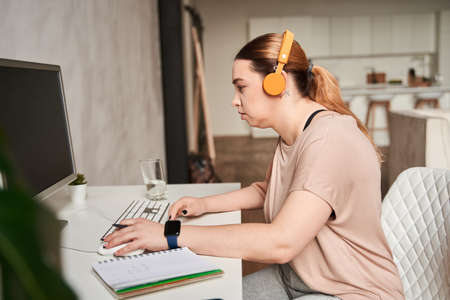 Calm caucasian female with artificial limb sitting at the table with her computer while working