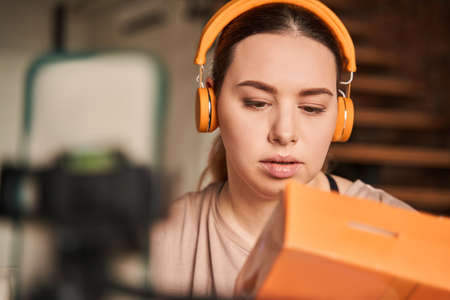 Woman blogger or coach sitting at home and shooting her blog on smartphoneの写真素材