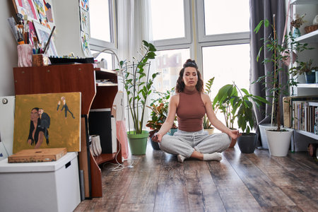 Mindful young woman sitting in lotus position at the floor at home