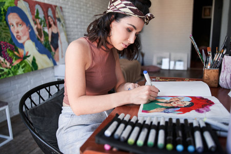 Female artist creative designer or illustrator sitting at the table and drawing her new art workの写真素材