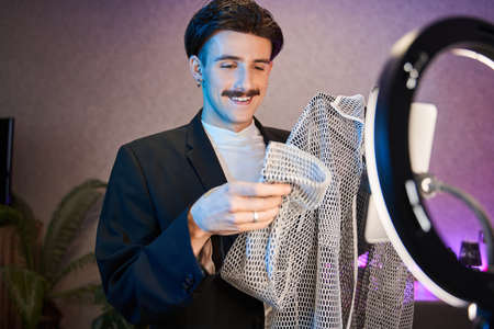 Man with mustache looking at the shirt while standing in front of the camera