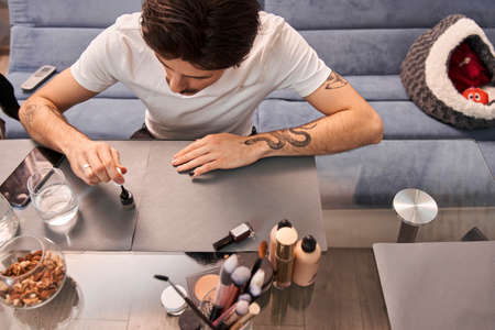 Brunette man making manicure. He is holding brush and preparing polishing fingernailsの写真素材
