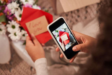 Woman holding greeting card with I love you signs at her hands while taking it from the bouquetの写真素材
