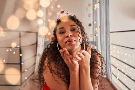 Multiracial woman sending air kiss to the camera while posing at her flat in fashionable clothesの写真素材