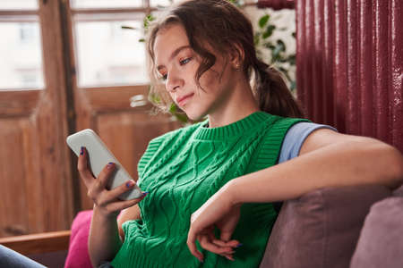 Pre-adolescent teen girl texting on her smart phone while sitting