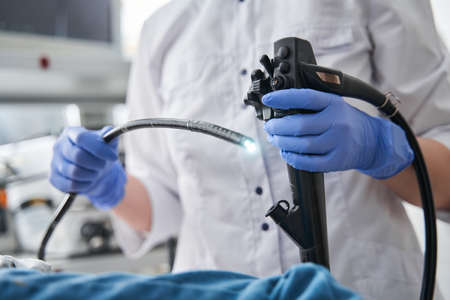Doctor holding endoscope during gastroscopy in hand while little girl patient laying