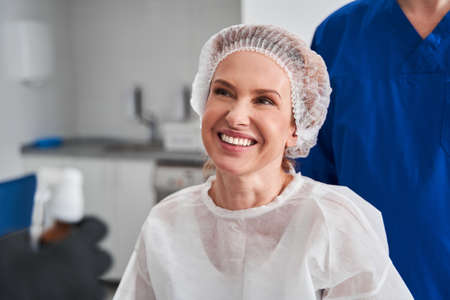 Happy caucasian woman wearing protective clothes laughing while waiting for the procedure