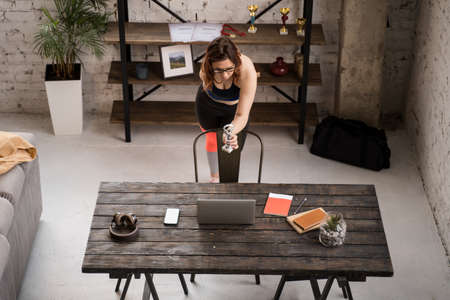 Handicap female in outfit for workout standing in front laptop and showing her prize