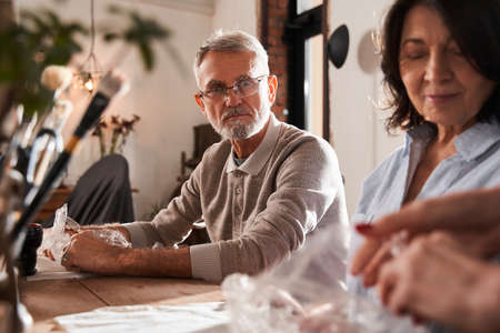 Grey haired bearded man looking with concentrated face at the teacher