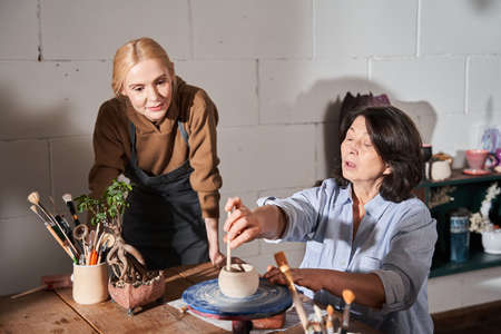 Beautiful brunette lady making clay pot in pottery workshopの写真素材