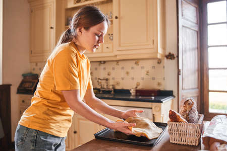 Teenage girl preparing dough for the pizza while cooking