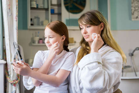 Caucasian mother and daughter looking at their reflection while sittingの写真素材
