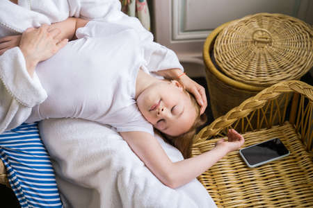 Cute child girl relaxing at her mother laps while spending time at the bathroom