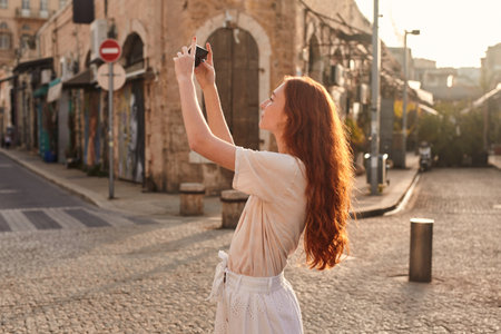 Ginger girl making photo of the ancient street or takingの写真素材