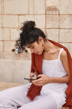 Woman sitting at the bench and chatting at her smartphone