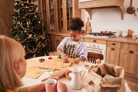 Female kid press cookies using diverse cutters while herの写真素材