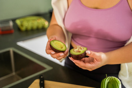 Cropped view of the female person holding two avocado piecesの写真素材