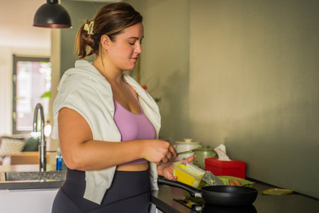 Full figured woman standing near the stove and cookingの写真素材