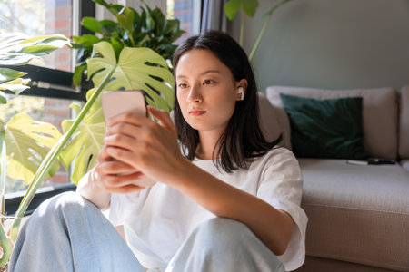 Brunette asian girl watching at the cellphone screenの写真素材