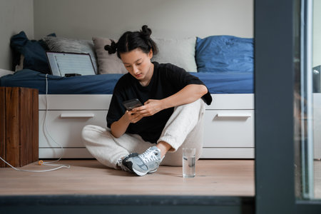 Teenager girl with cute hairstyle sitting at the floor nearの写真素材
