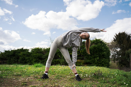 Strong teen girl standing and stretching herself at the park