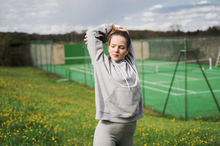 Serene teen girl wearing earphones warming up and stretchingの写真素材