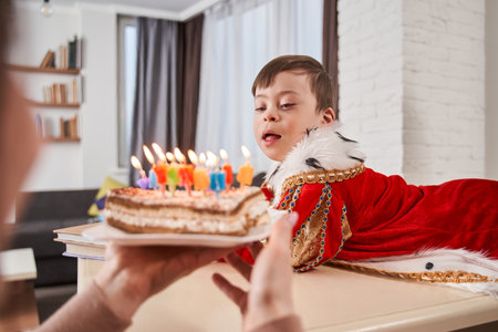Mother bringing cake with candles to her baby boy with Downの写真素材