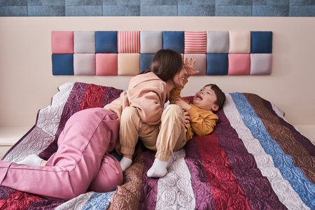 Mom enjoying time with her son, while playing at the bed and