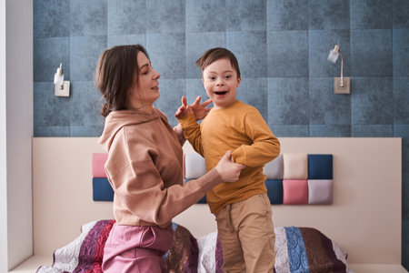 Boy with Down syndrome playing with his mother at the bed atの写真素材