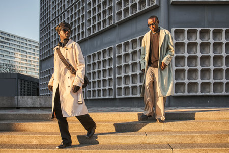 Fashionable photo of two multiracial men models crossing down stairs