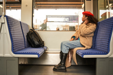 Full length view of attractive young lady in earphones looking at the window and enjoying musicの写真素材