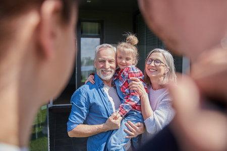 Senior couple holding little girl at the hands and feeling happy at the summer