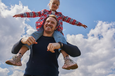 Cheerful family of father and child girl playing at summer streetの写真素材