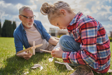 Concentrated child holding toy while playing with her grey haired grandfatherの写真素材