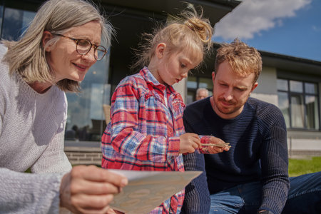 Senior grandmother and adult man playing with little girlの写真素材