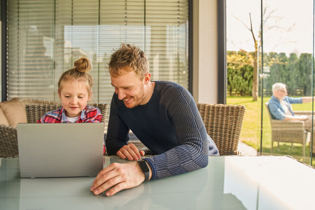 Portrait of beaming father and outgoing girl watching at applianceの写真素材