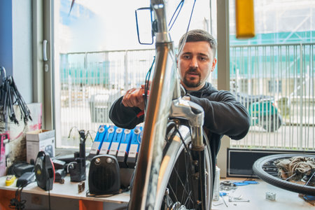 Serious bike mechanic examining and repairing bicycle in workshopの写真素材