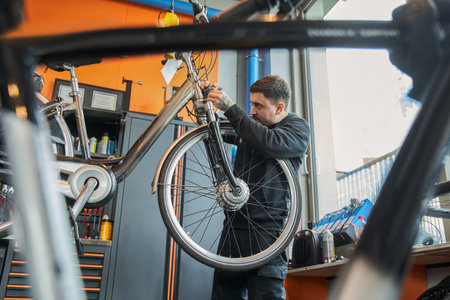 Serious guy standing near handing bike and looking attentivelyの写真素材