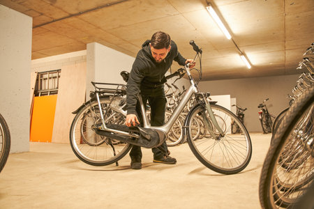 Male bike store worker taking bicycle while preparing it for the sellingの写真素材