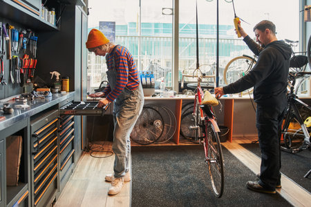 Full length view of the female bicycle mechanic taking details from box while repairing bicyclesの写真素材