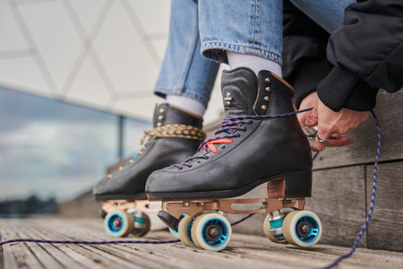 Cropped view of the adult woman tying laces at her roller boots
