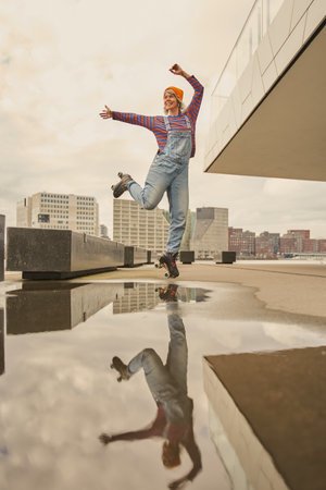 Vertical view of the cheerful lady dancing on roller skates outside on urban street