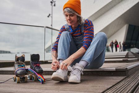 Calm adult woman changing footwear while sitting at the urban place