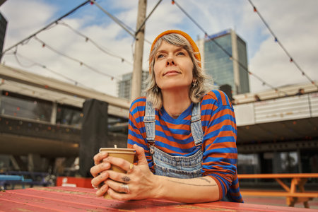 Happy adult caucasian woman smiling and sitting at the street cafeの写真素材
