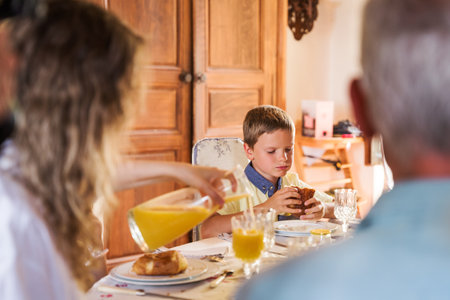 Cute little boy having breakfast with his family at the morning in kitchenの写真素材